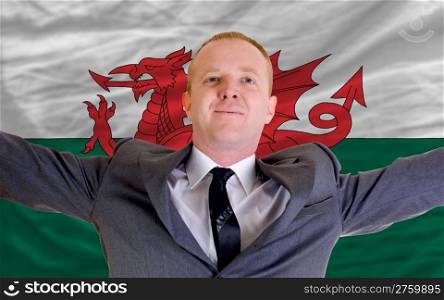 joyful investor spreading arms after good business investment in wales, in front of flag