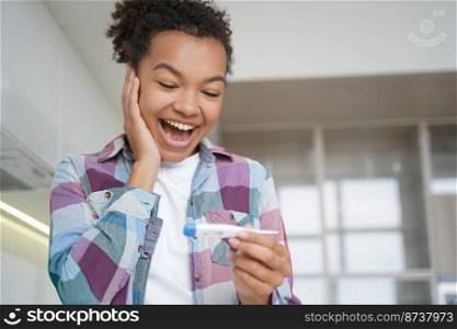 Joyful mixed race teen girl checking her body temperature with thermometer before travelling. Happy delighted young lady celebrates convalescence, has no covid coronavirus symptoms during pandemic.. Joyful mixed race girl checking body temperature with thermometer before trip, has no covid symptom