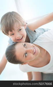 Joyful toddler on back of his mother - family enjoying moments of happiness