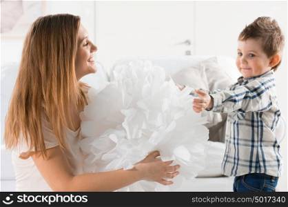 Joyful toddler playing with paper home decoration and his mother