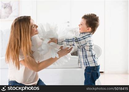 Joyful toddler playing with paper home decoration and his mother