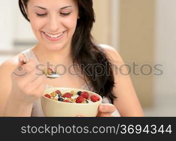 Joyful woman eating healthy cereal for breakfast