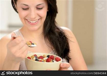 Joyful woman eating healthy cereal for breakfast