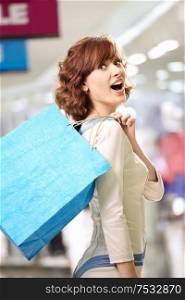 Joyful woman standing in a half-turn in shop with bags