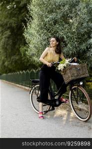 Joyful woman with flowers in the basket of electric bike