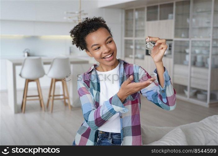 Joyful young african american woman showing house keys at new home. Biracial teen girl homeowner, tenant feels happiness with relocation or purchase of flat. Real estate rent, first own apartment.. Joyful teen girl homeowner, tenant holds keys to new house. Real estate rent, first own apartment