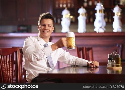 Joyous young man holding a mug of beer