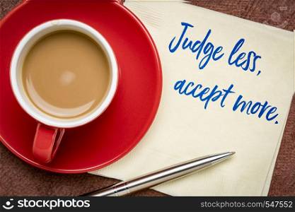 judge less, accept more - inspirational handwriting on a napkin with a cup of coffee