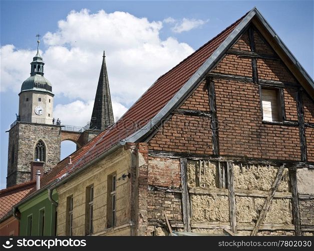 Jueterbog-Nikolaikirche-Fachwerkbau. towers of st. nicholas church in Jueterbog behind the gable of an old house
