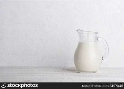 Jug of milk on white wooden table with side copy space