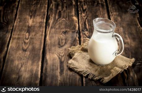 Jug with milk on a sack. On a wooden table.. Jug with milk on a sack.