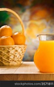 jug with orange juice and oranges in busket
