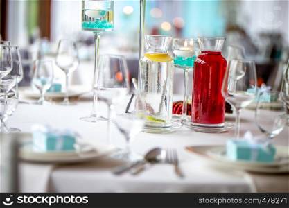 Jugs with lemonade on table with food at wedding party or banquet. Water with fresh lemon and red limonade on the table. Focus on jug with red lemonade.