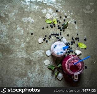 Juice and milk smoothie with berries. On a stone background.. Juice and milk smoothie with berries. On stone background.