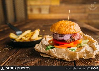 Juice burger with fresh steak on wooden table closeup, nobody. Hamburger with beefstek, food preparation, cooking
