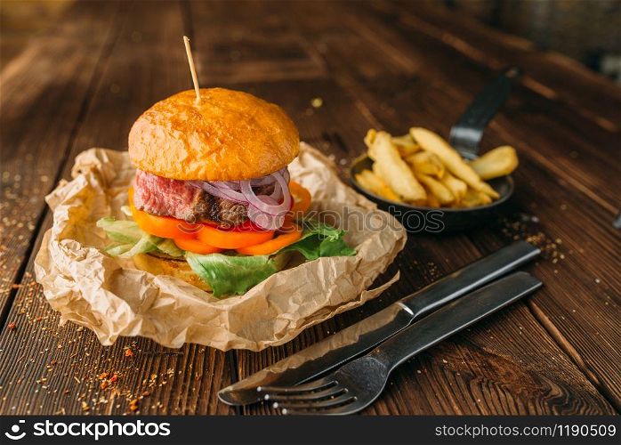 Juice burger with fresh steak on wooden table closeup, nobody. Hamburger with beefstek, food preparation, cooking. Juice burger with steak on wooden table closeup