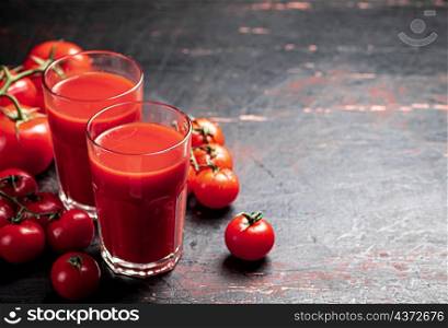 Juice from ripe tomatoes in a glass. On a rustic dark background. High quality photo. Juice from ripe tomatoes in a glass.