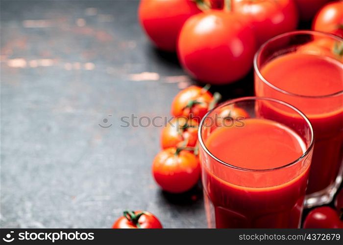 Juice from ripe tomatoes in a glass. On a rustic dark background. High quality photo. Juice from ripe tomatoes in a glass.