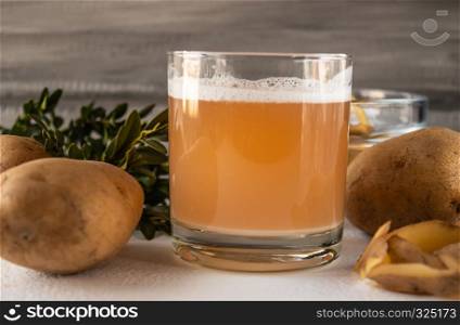 Juice in a glass with potatoes. Potatoes on a white background.