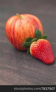juicy apple and strawberry on a wooden surface