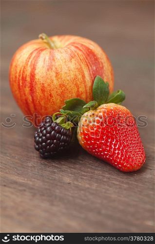 juicy apple,blackberry and strawberry on a wooden surface