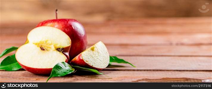 Juicy apples with leaves on the table. On a wooden background. High quality photo. Juicy apples with leaves on the table.
