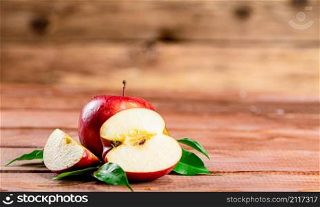 Juicy apples with leaves on the table. On a wooden background. High quality photo. Juicy apples with leaves on the table.