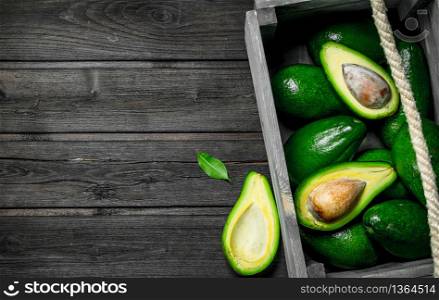 Juicy avocado and pieces of avocado in a wooden box. On a black wooden background.. Juicy avocado and pieces of avocado in a wooden box.
