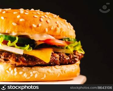 Juicy beef burger with cutlet, onion, vegetables, melted cheese, lettuce, sauce and topped sesame seeds. Isolated hamburger rotates on dark smoke background, close-up view.. Juicy beef burger with cutlet, onion, vegetables, melted cheese, lettuce, sauce and topped sesame seeds. Isolated hamburger rotates on dark smoke background, close-up view