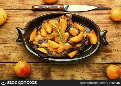 Juicy beef meat in apricot sauce.Veal steak in fruit marinade on old wooden background. Veal steak fried with apricots