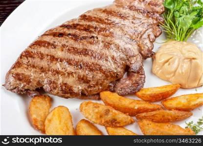 Juicy beef steak stuffed with beef tongue and cheese served with potatoes, greenery and sauce