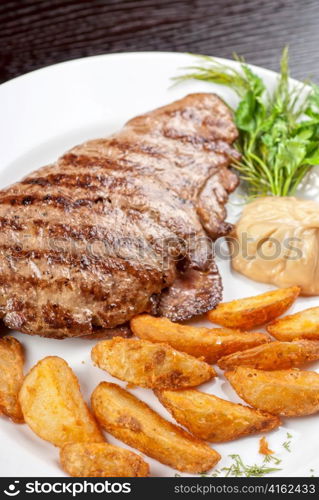 Juicy beef steak stuffed with beef tongue and cheese served with potatoes, greenery and sauce