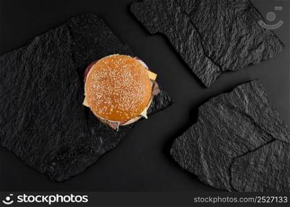 juicy cheeseburger on a background of black stone plates. the view from the top. fast food on the black stone