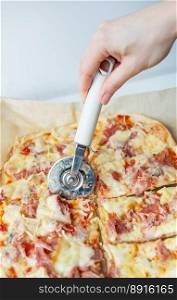 Juicy delicious slice of pizza with ham, onion and cheese. The chef cuts the pizza into pieces with a knife. Cooking pizza at home. Juicy delicious slice of pizza with ham, onion and cheese. The chef cuts the pizza into pieces with a knife. Cooking pizza at home.