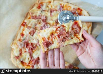 Juicy delicious slice of pizza with ham, onion and cheese. Pizza knife on the background. Cooking pizza at home, the girl holds a piece of pizza in her hands. Juicy delicious slice of pizza with ham, onion and cheese. Pizza knife on the background. Cooking pizza at home, the girl holds a piece of pizza in her hands.