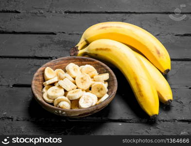 Juicy fresh bananas and banana slices in a plate. On rustic background.. Juicy fresh bananas and banana slices in a plate.