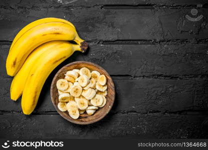 Juicy fresh bananas and banana slices in a plate. On rustic background.. Juicy fresh bananas and banana slices in a plate.