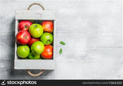 Juicy fresh green and red apples in a wooden box.On white rustic background.. Juicy fresh green and red apples in a wooden box.
