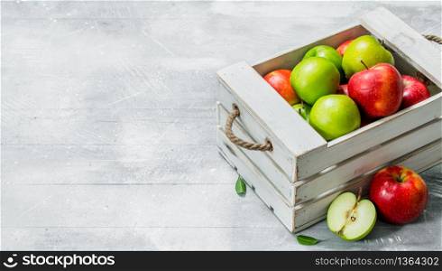 Juicy fresh green and red apples in a wooden box.On white rustic background.. Juicy fresh green and red apples in a wooden box.
