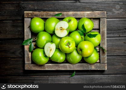 Juicy green apples and Apple slices in a wooden box. On a dark wooden background.. Juicy green apples and Apple slices in a wooden box.