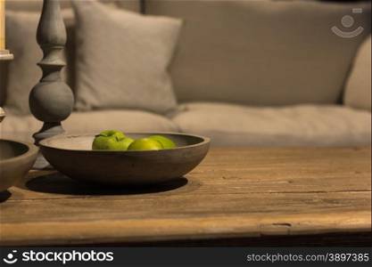 Juicy Green Apples in Handcrafted Wooden bowl on Rustic Wood Table with Sofa in Background