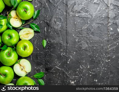 Juicy green apples with leaves and slices of apples. On a dark rustic background.. Juicy green apples with leaves and slices of apples.