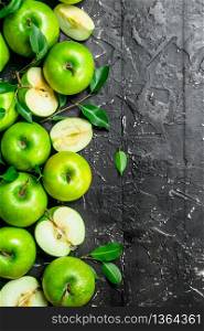 Juicy green apples with leaves and slices of apples. On a dark rustic background.. Juicy green apples with leaves and slices of apples.