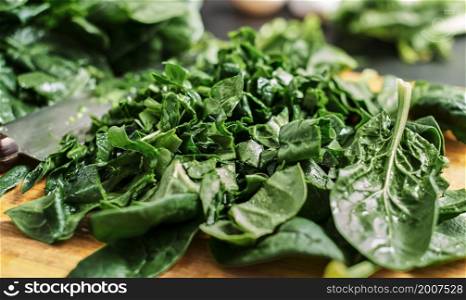 Juicy green sliced spinach leaves lie on a wooden cutting board. Selective focus, close-up of spinach. The idea of making breakfast from organic healthy food