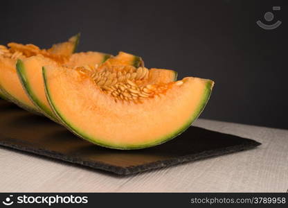 Juicy honeydew melon on a black slate tray.