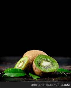 Juicy kiwi with greens on the table. On a black background. High quality photo. Juicy kiwi with greens on the table.