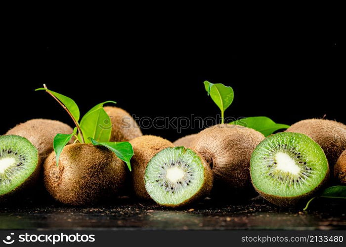 Juicy kiwi with greens on the table. On a black background. High quality photo. Juicy kiwi with greens on the table.