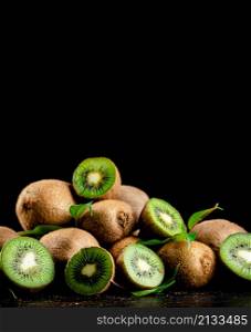 Juicy kiwi with greens on the table. On a black background. High quality photo. Juicy kiwi with greens on the table.