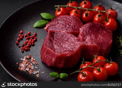 Juicy raw beef with spices, salt and herbs on a dark concrete background. Preparing to cook a meat dish. Juicy raw beef with spices, salt and herbs on a dark concrete background