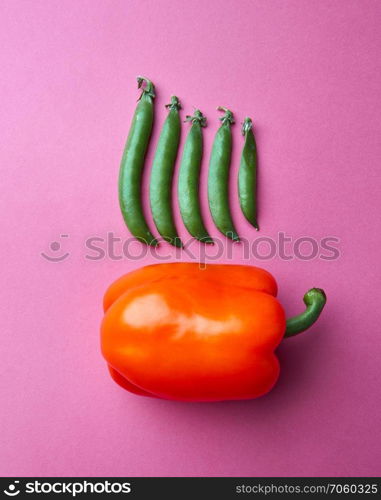 Juicy ripe pepper and green peas pods on a pink background. The concept of healthy organic food.. A set of orange peppers and different peas pods on a pink paper background. Organic vegetables. Top view
